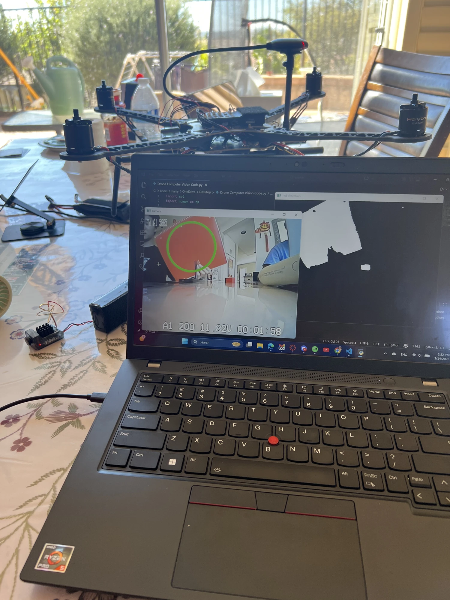 Laptop showing Python OpenCV red detection with a circled target and white-on-black mask