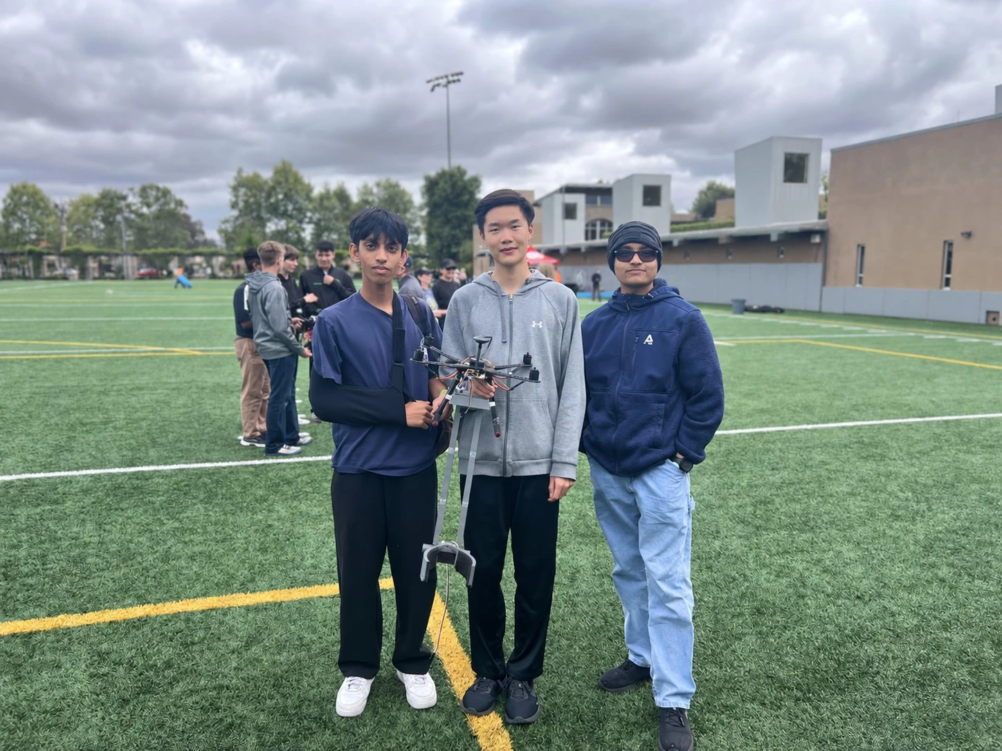Three teammates with the drone on a field