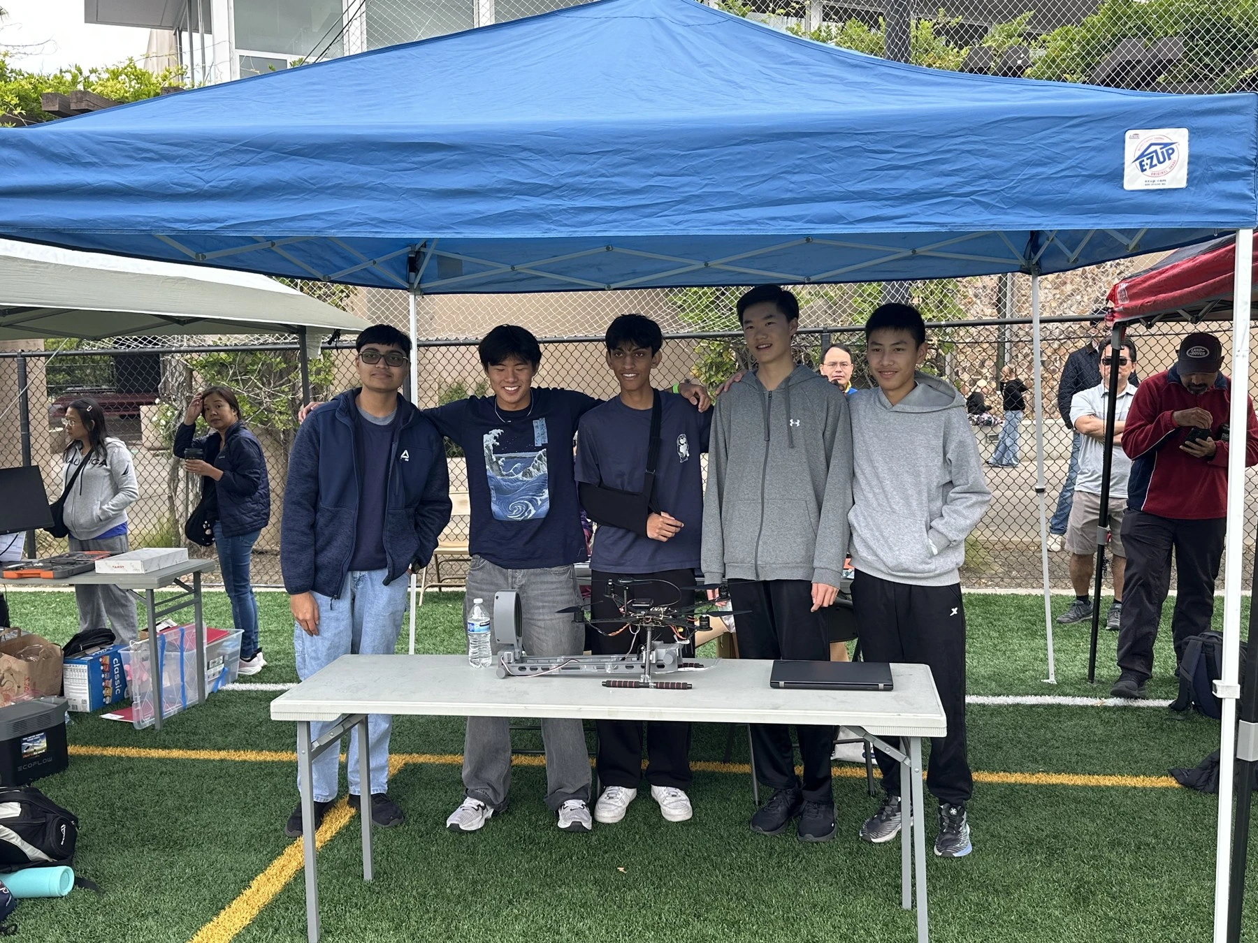 Team with the drone beneath a blue canopy