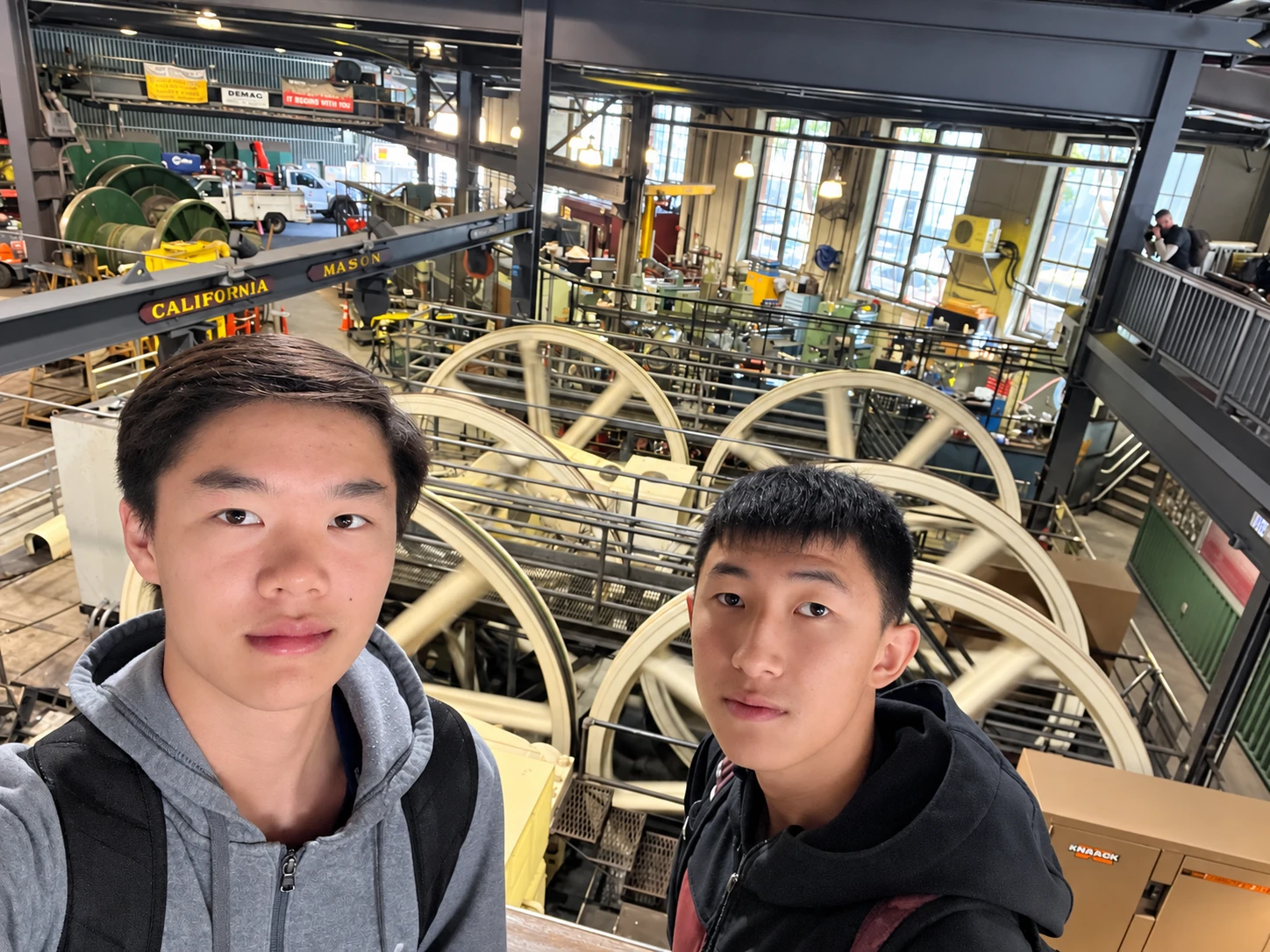 Two students overlooking large machinery and flywheels